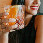 femme buvant une boisson fraîche et souriant, dents visibles