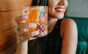 femme buvant une boisson fraîche et souriant, dents visibles
