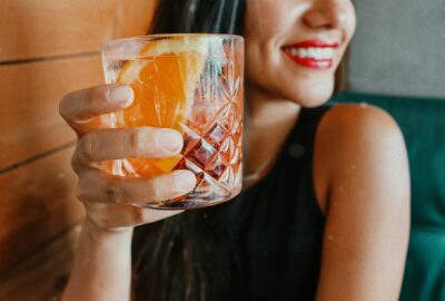 femme buvant une boisson fraîche et souriant, dents visibles